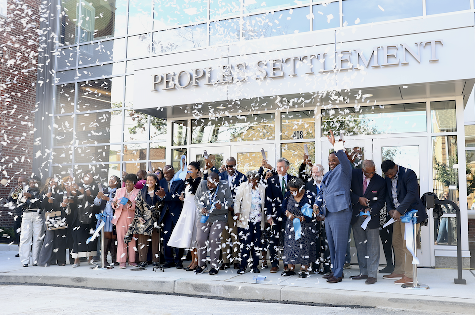community gathers in front of the new Peoples Settlement building with confetti in the air
